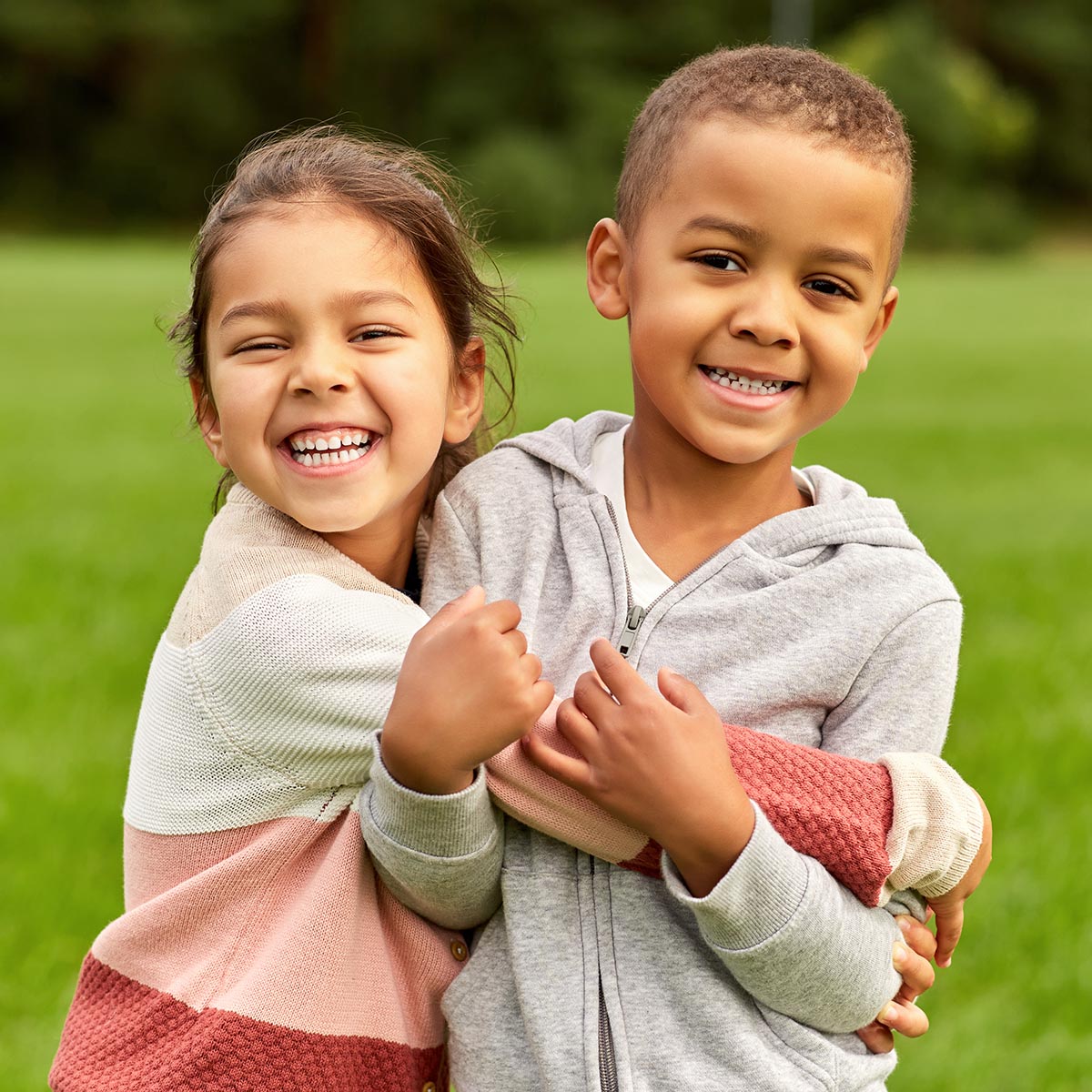 childhood, leisure and people concept - happy smiling little boy and girl hugging at park